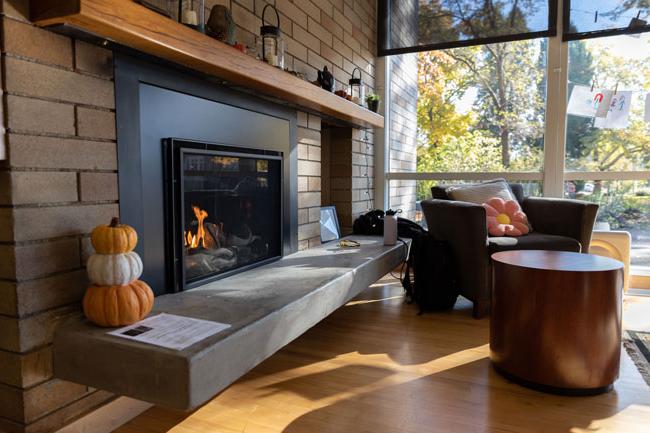 点燃的壁炉配有软垫扶手椅和秋季装饰
